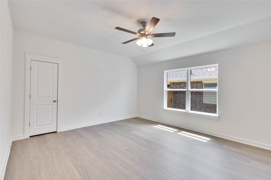 Spacious room featuring light wood-finish flooring, a white trim package, and a large window