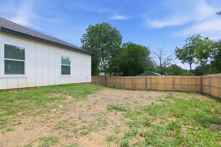 Expansive backyard featuring a natural ground cover and a wood privacy fence