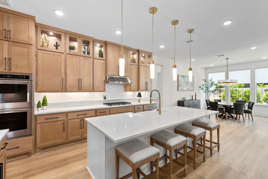 The gourmet kitchen features quartz countertops, custom cabinetry with display uppers, stainless steel appliances, and designer pendant lighting.