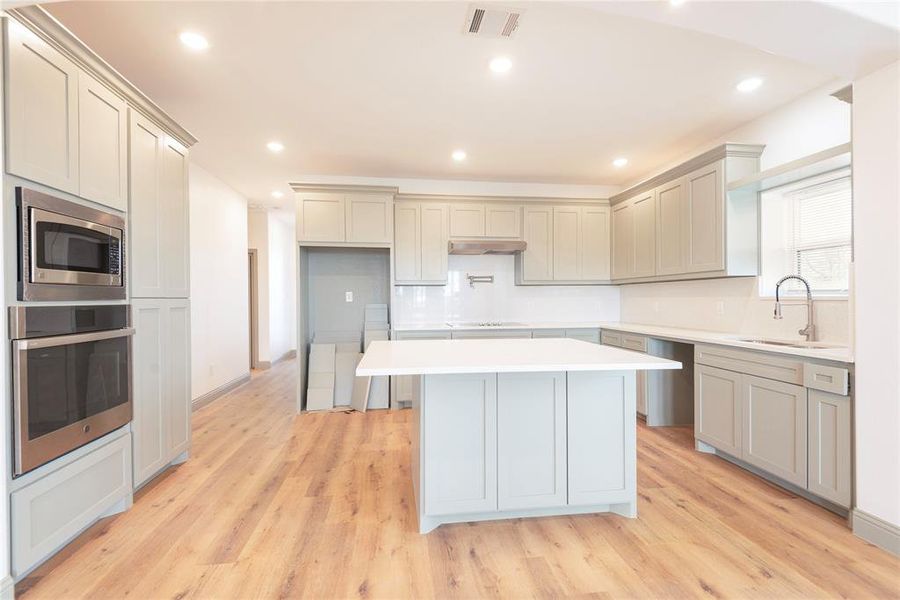 Kitchen with appliances with stainless steel finishes, a breakfast bar, tasteful backsplash, recessed lighting, and light wood-style floors