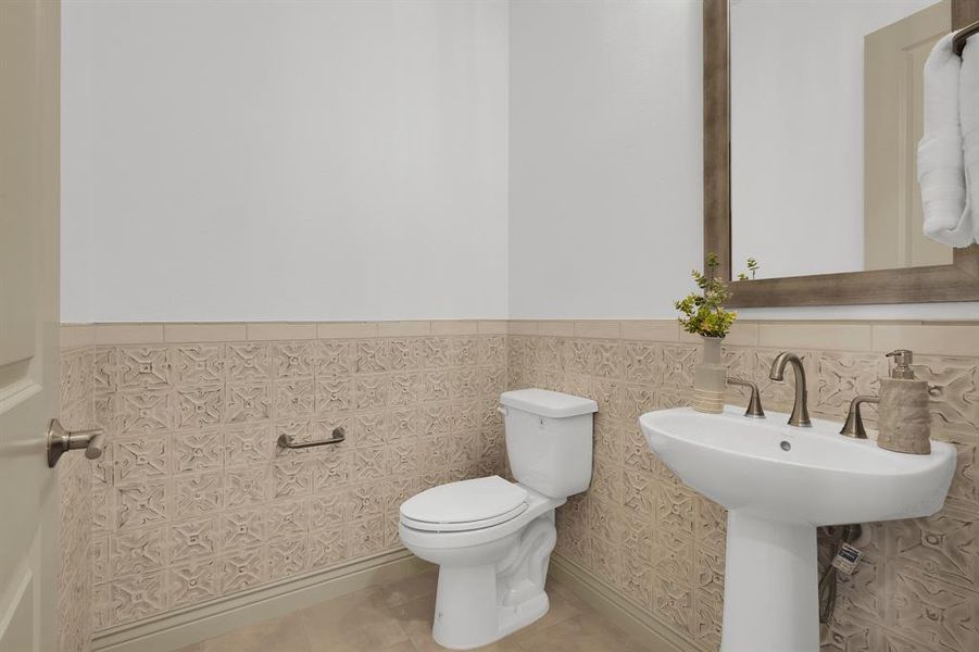 Half bathroom featuring a wainscoted wall, tile patterned flooring, and tile walls
