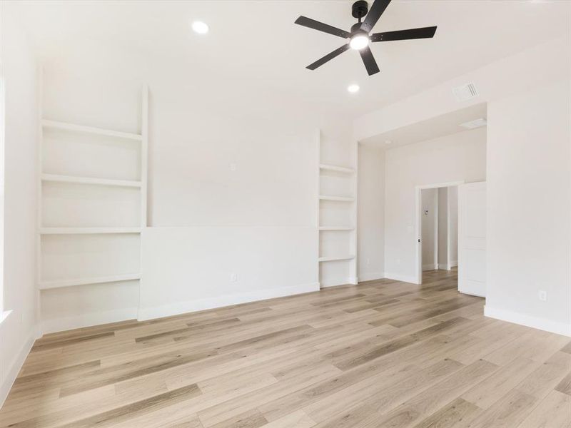 Empty room featuring built in features, light wood finished floors, ceiling fan, and recessed lighting
