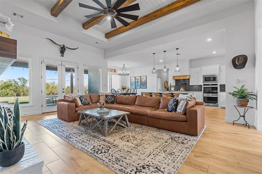 Living room featuring beamed ceiling, light wood-type flooring, and wood ceiling