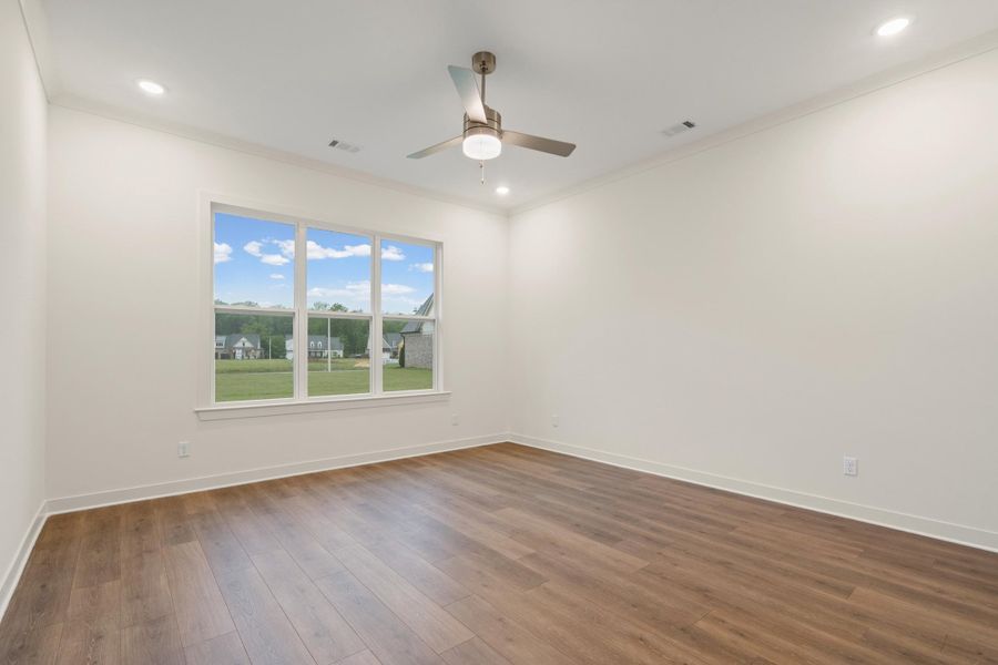 Spacious room featuring wood-finish flooring and a multi-pane window Spacious room featuring wood-finish flooring and a multi-pane window