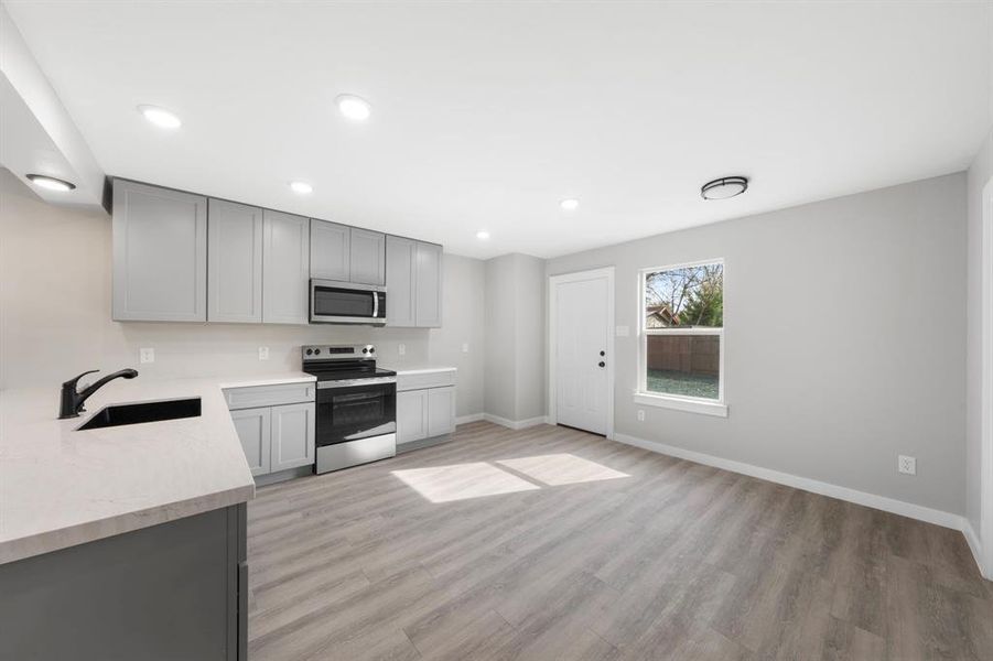 Kitchen with gray cabinetry, stainless steel appliances, light wood-style flooring, and recessed lighting Kitchen with gray cabinetry, stainless steel appliances, light wood-style flooring, and recessed lighting