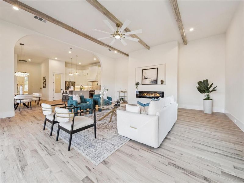 Living room with beam ceiling, ceiling fan, and light wood-type flooring