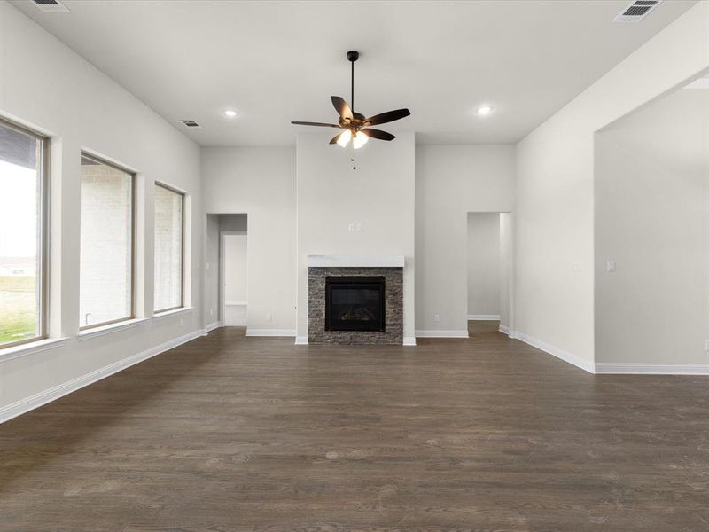 Unfurnished living room featuring a glass covered fireplace, a ceiling fan, dark wood-style flooring, and recessed lighting