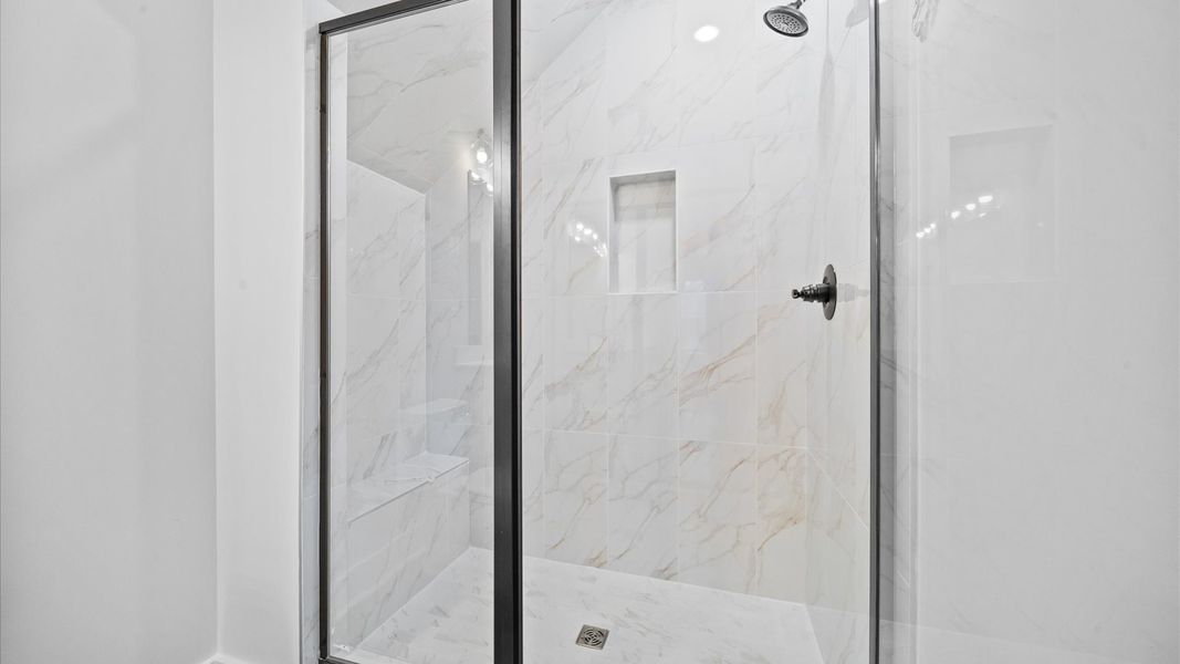 Memorable mornings begin in this elegant primary bathroom with tiled walk-in shower and double vanity Memorable mornings begin in this elegant primary bathroom with tiled walk-in shower and double vanity