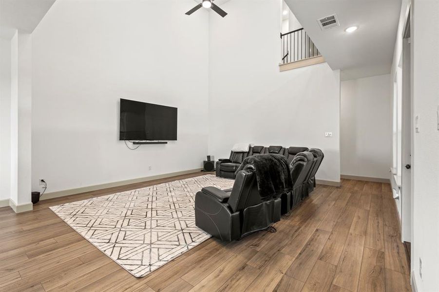 Cinema room featuring wood finished floors, a high ceiling, recessed lighting, and ceiling fan