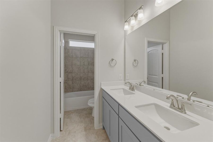 Double vanity with integrated sinks, brushed nickel fixtures, and light gray cabinetry