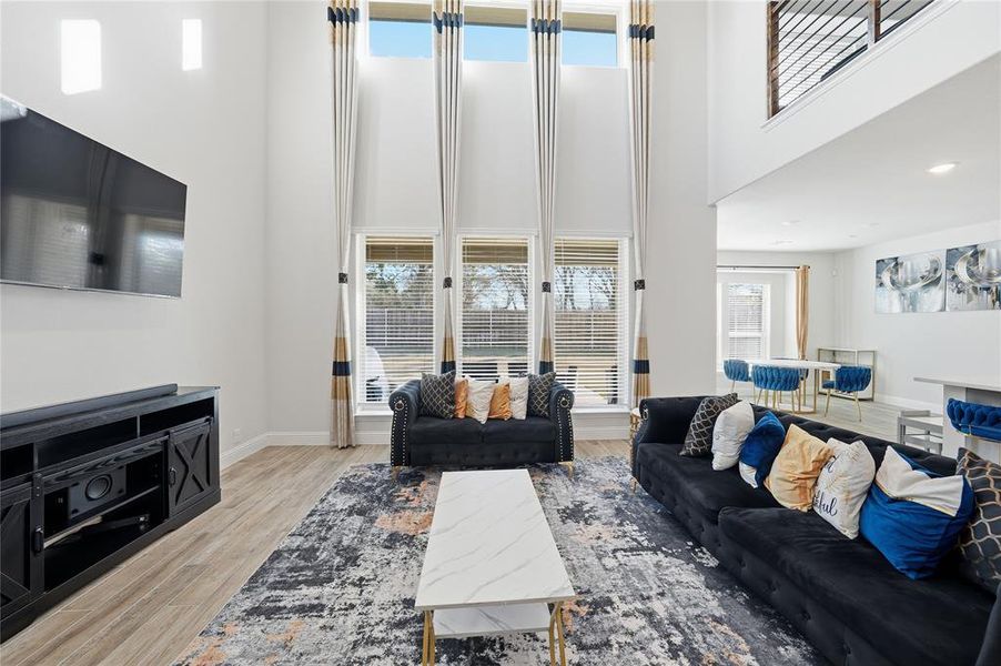 Living area with light wood-type flooring and a towering ceiling