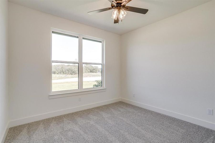 Carpeted spare room with plenty of natural light and ceiling fan