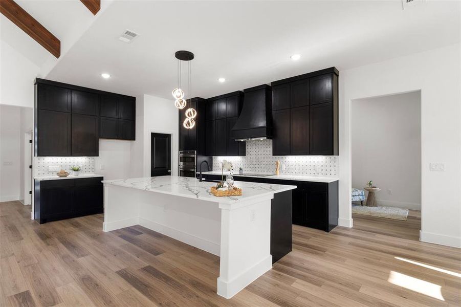 Kitchen with dark cabinets, tasteful backsplash, and light stone counters