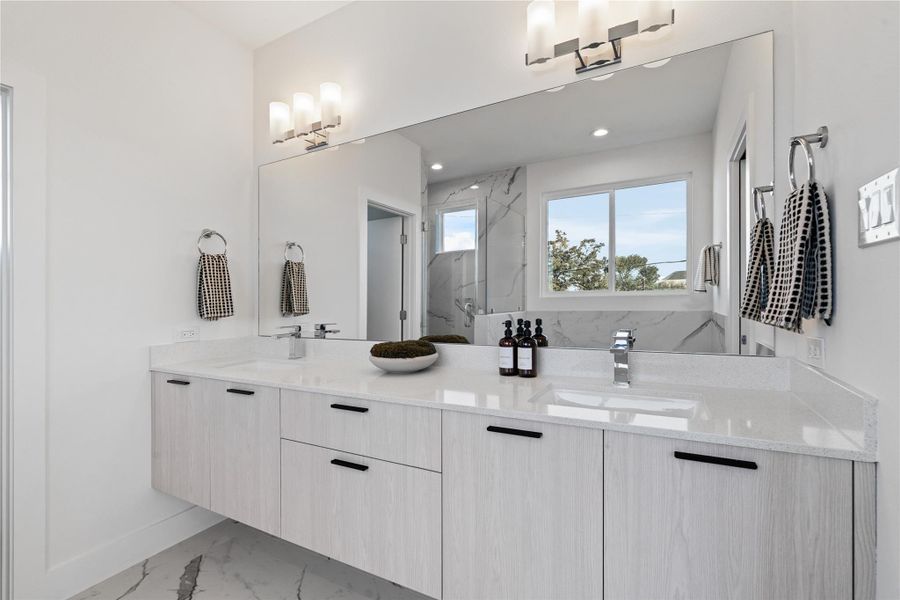 Floating double vanity with ample storage, a large framed mirror & custom lighting that brings a touch of sophistication to the primary bath. Floating double vanity with ample storage, a large framed mirror & custom lighting that brings a touch of sophistication to the primary bath.