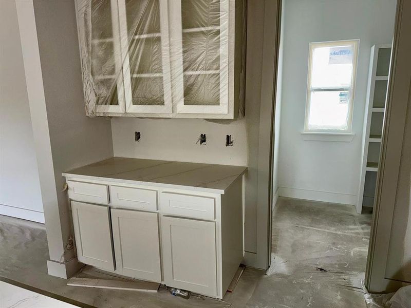 Bar area with white cabinets, concrete floors, and light countertops Bar area with white cabinets, concrete floors, and light countertops