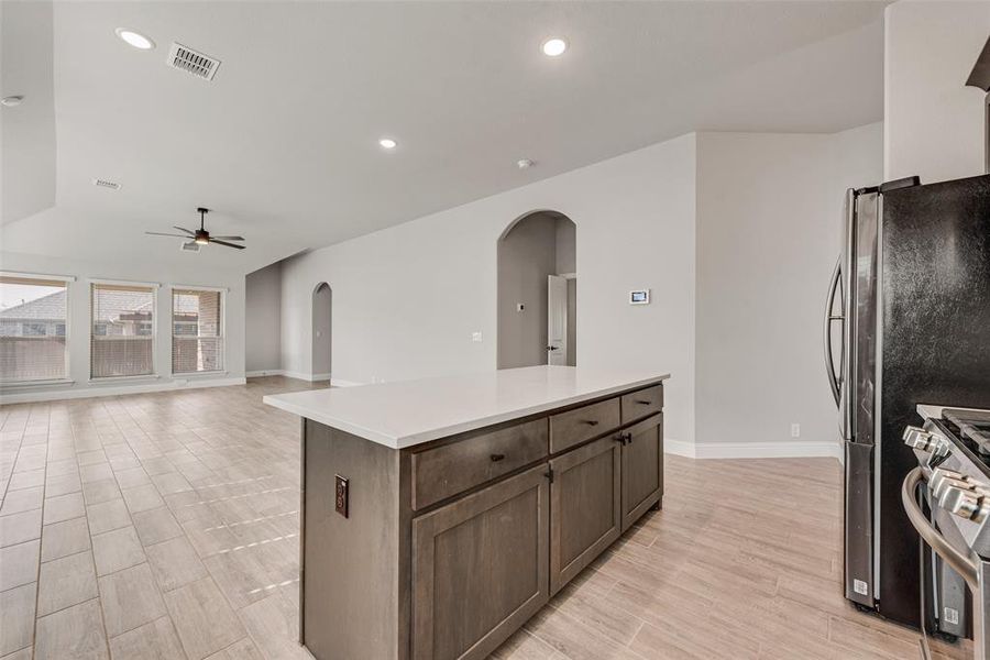 Kitchen featuring arched walkways, wood tiled floors, a center island, recessed lighting, and appliances with stainless steel finishes Kitchen featuring arched walkways, wood tiled floors, a center island, recessed lighting, and appliances with stainless steel finishes