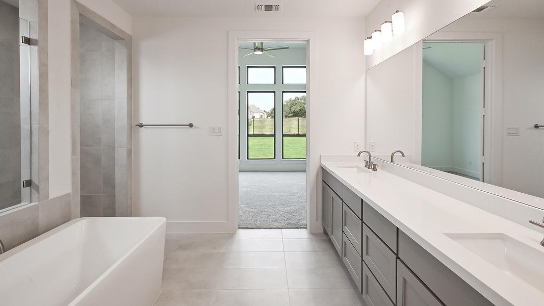 Full bath with a freestanding tub, a ceiling fan, double vanity, tile patterned floors, and baseboards Full bath with a freestanding tub, a ceiling fan, double vanity, tile patterned floors, and baseboards