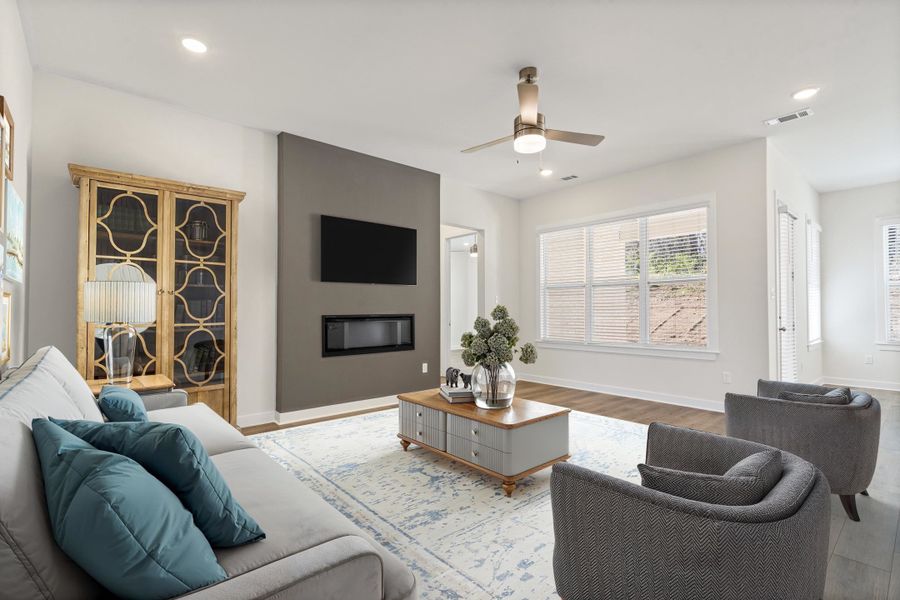 Living area with a ceiling fan, wood finished floors, a glass covered fireplace, and recessed lighting