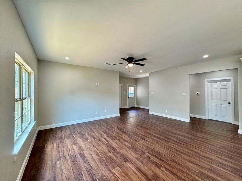 Unfurnished room featuring ceiling fan, wood-type flooring, and a wealth of natural light