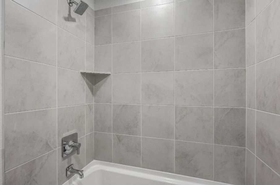 A bathroom with a bathtub and tile walls. A bathroom with a bathtub and tile walls.