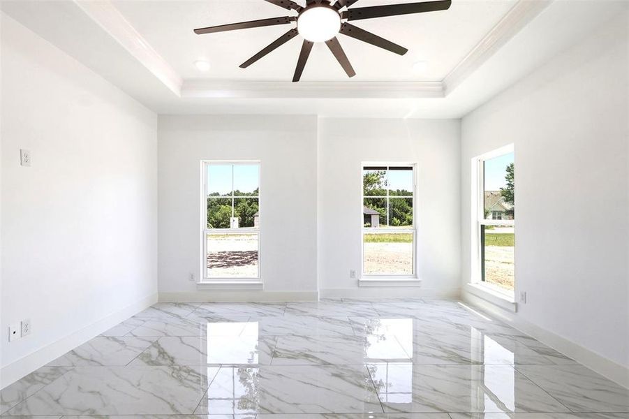 Spacious room featuring white walls, high ceilings with a multi-blade ceiling fan, recessed lighting, and tray ceiling detailing