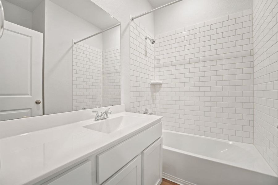 Crisp subway tile lines the shower surround adjacent to a clean white vanity.