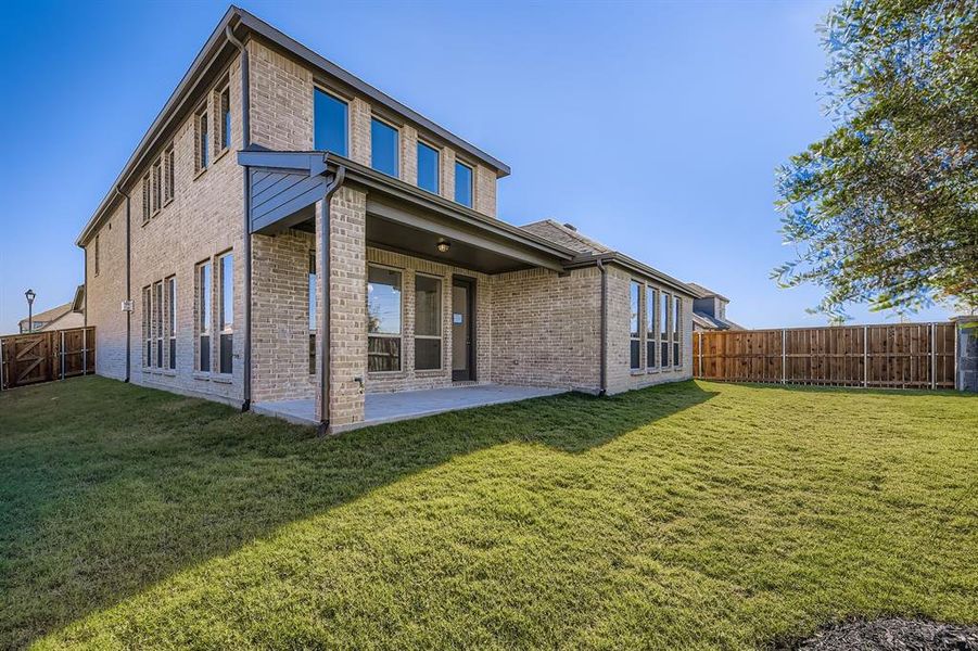 Rear view of house featuring brick siding, a patio area, and a fenced backyard