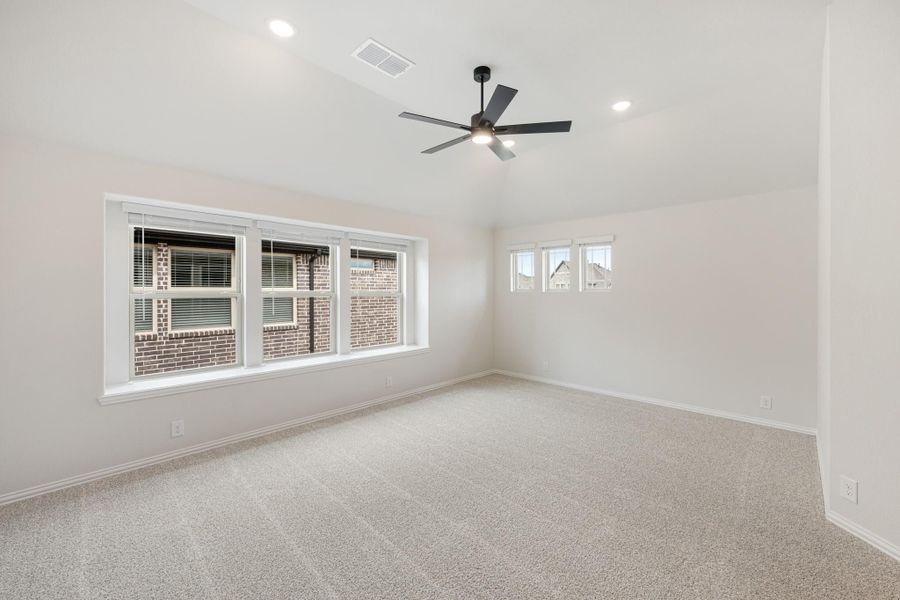 Empty bedroom with carpet flooring, ceiling fan, and large windows with natural light Empty bedroom with carpet flooring, ceiling fan, and large windows with natural light