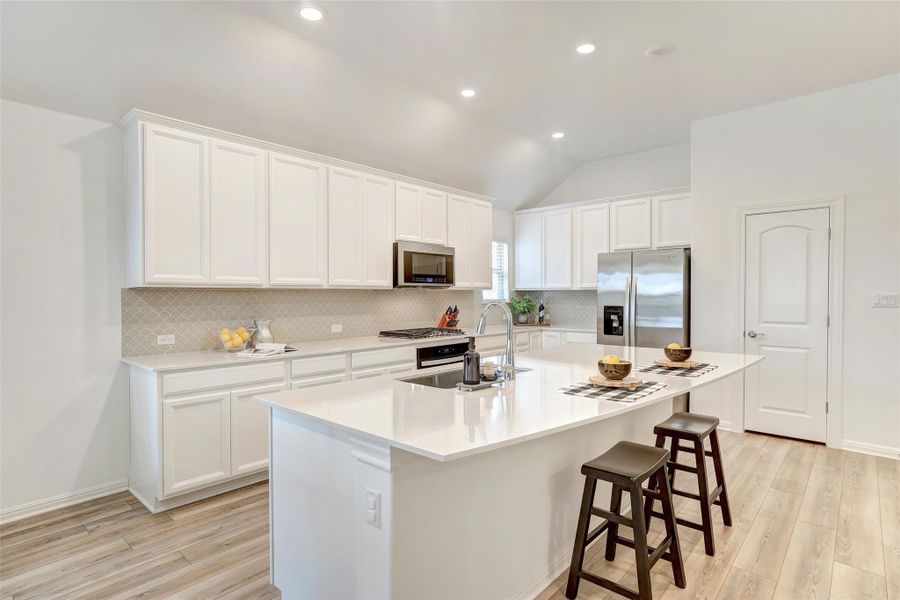 Kitchen with stainless steel appliances, decorative backsplash, light wood-type flooring, lofted ceiling, and recessed lighting