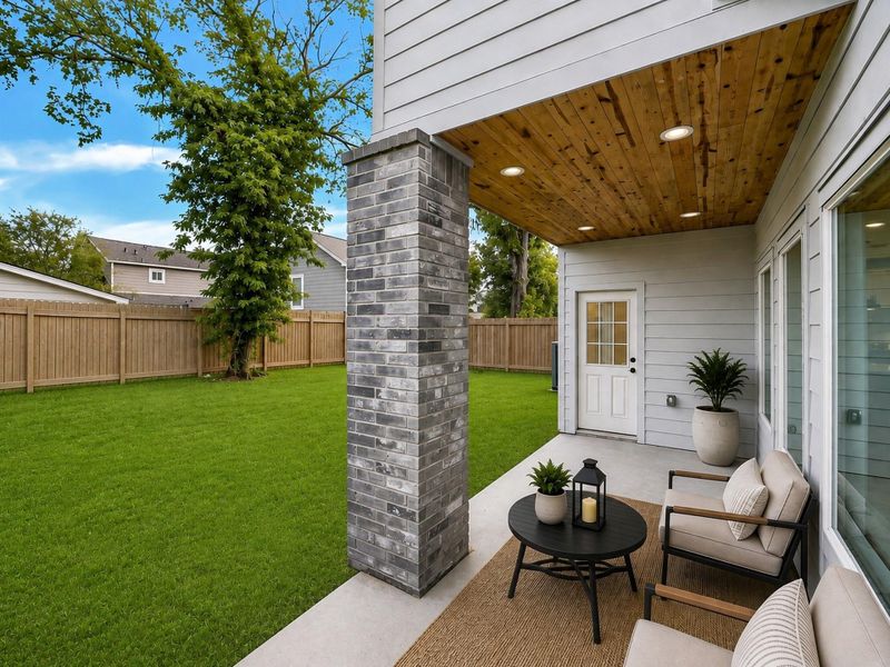 Inviting covered backyard patio overlooking a spacious fenced yard, offering the perfect setting for outdoor relaxation and entertaining