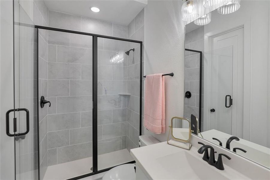 Contemporary bathroom featuring a walk-in shower with black-framed glass enclosure, light grey subway tile, and matte black fixtures