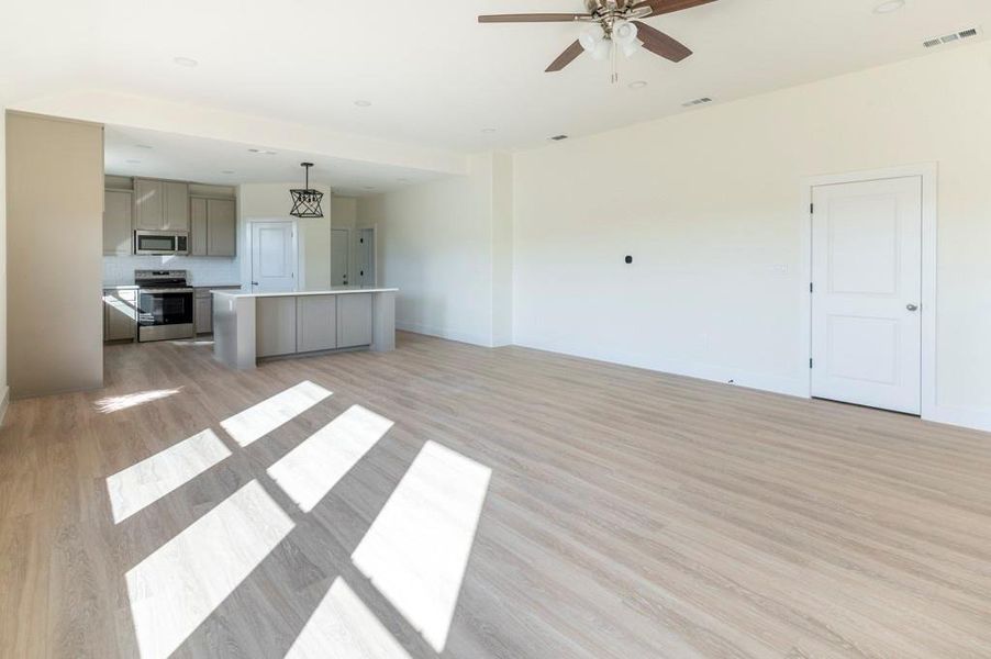Unfurnished living room featuring light wood-type flooring, ceiling fan, and recessed lighting