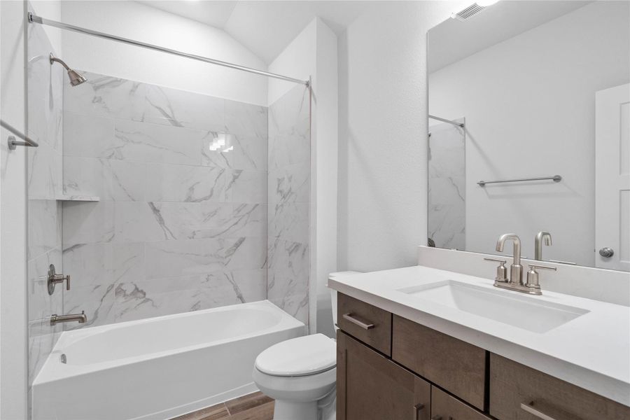 This bright secondary bathroom features stained cabinetry, quartz countertop and a tub/shower combination - ideal for both quick showers and relaxing baths for children or guests. This bright secondary bathroom features stained cabinetry, quartz countertop and a tub/shower combination - ideal for both quick showers and relaxing baths for children or guests.