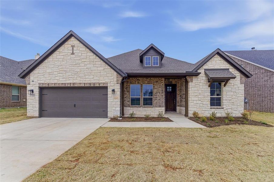 View of front of house with an attached garage, stone siding, a porch, driveway, and a shingled roof
