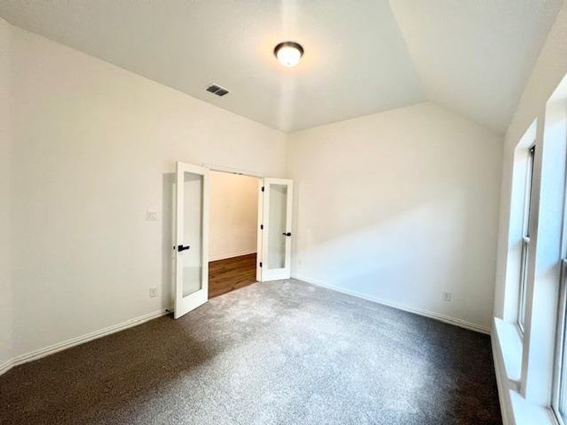 Unfurnished bedroom with french doors, baseboards, visible vents, and lofted ceiling Unfurnished bedroom with french doors, baseboards, visible vents, and lofted ceiling