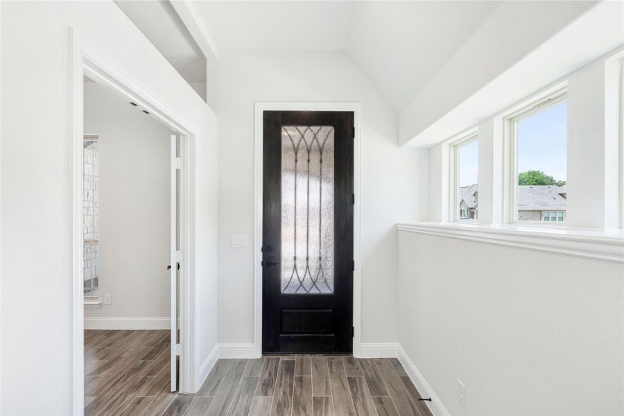 Entryway with dark wood front door featuring decorative glass panel, vaulted ceiling, and wood-look tile floors Entryway with dark wood front door featuring decorative glass panel, vaulted ceiling, and wood-look tile floors