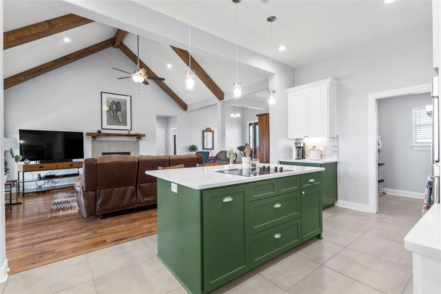 Kitchen featuring dual tone cabinetry, a kitchen island with sink, light tile patterned floors, open floor plan, and hanging light fixtures