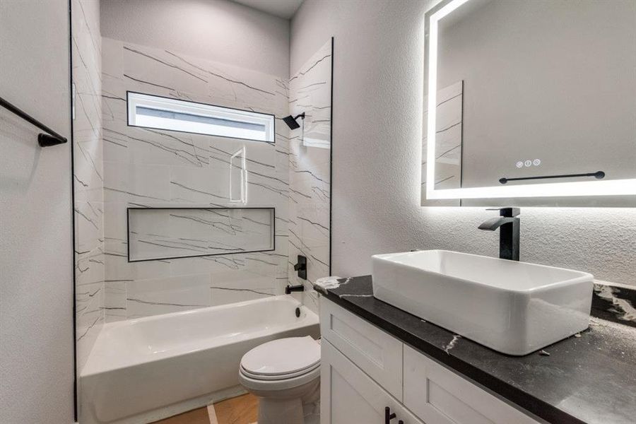 Full bathroom with vanity, tiled shower / bath, and toilet