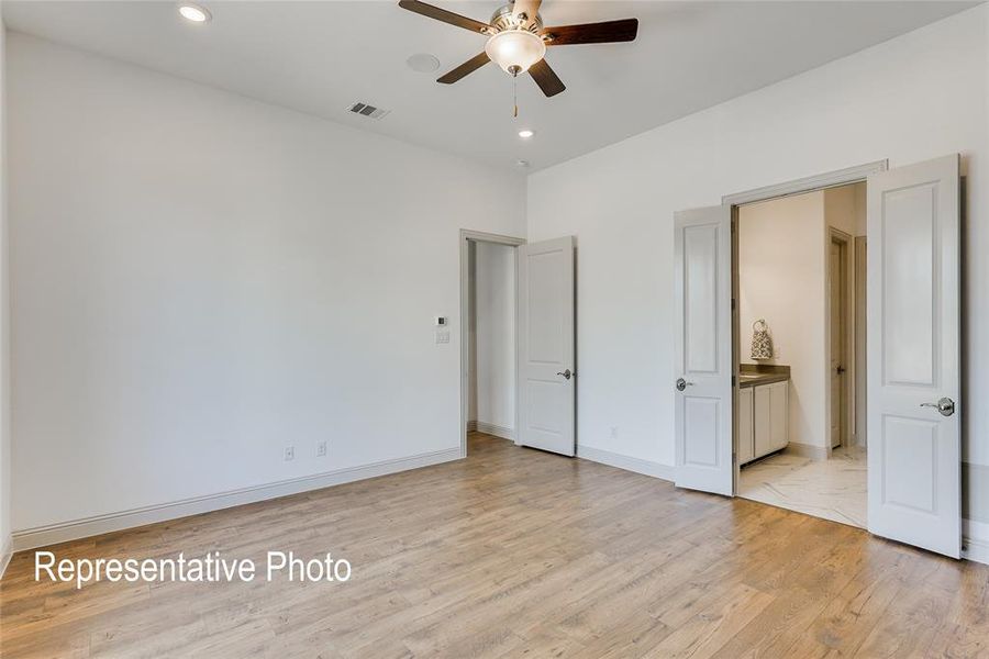 Unfurnished bedroom featuring ensuite bathroom, ceiling fan, and light wood-type flooring