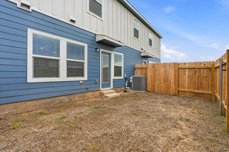 Private fenced yard with a wood privacy fence, blue horizontal siding, white trim windows, and a glass-paneled door Private fenced yard with a wood privacy fence, blue horizontal siding, white trim windows, and a glass-paneled door