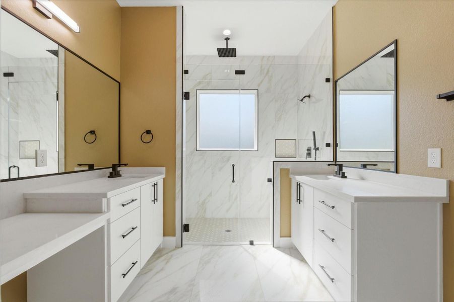 The primary bathroom offers a private water closet, a dedicated vanity area for added convenience, dual sinks and a walk-in shower with matching tile flooring.
