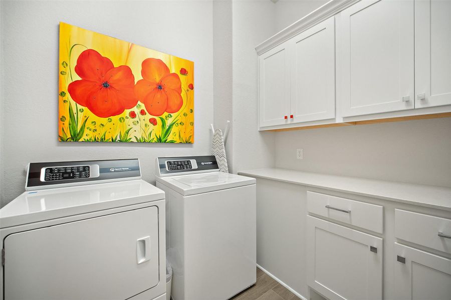 Washroom with washer and clothes dryer, cabinet space, and light wood finished floors