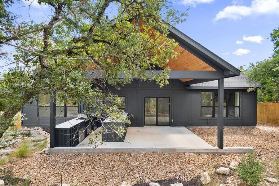 Rear view of property with a patio area, a shingled roof, and board and batten siding Rear view of property with a patio area, a shingled roof, and board and batten siding