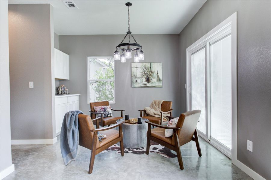 Sitting area with finished concrete floors, a chandelier, and baseboards