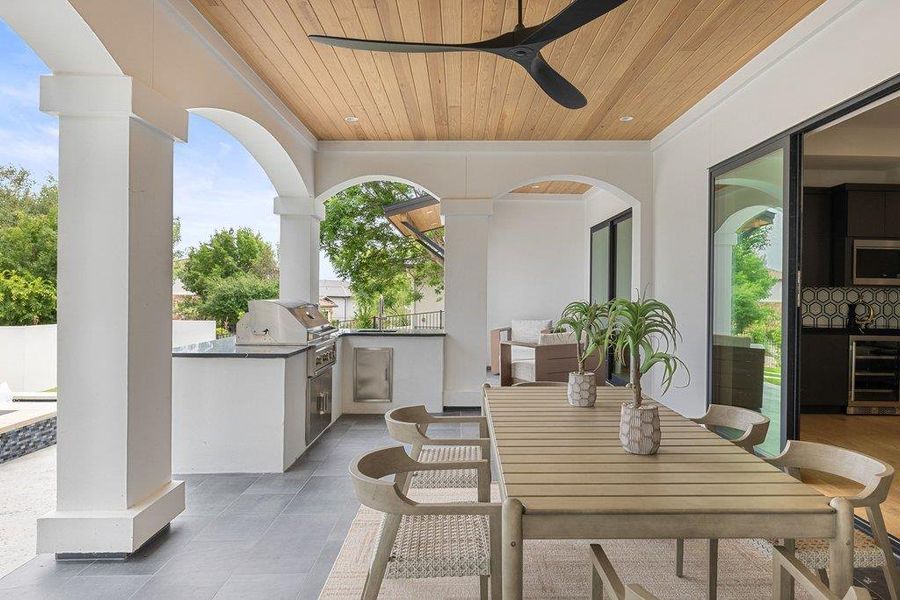 Covered outdoor patio featuring a wood-panel ceiling, architectural columns, and dark tile flooring