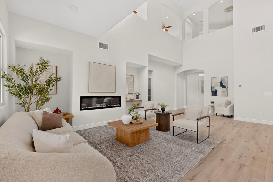 Double-height ceilings and a sleek linear fireplace define this airy living space.