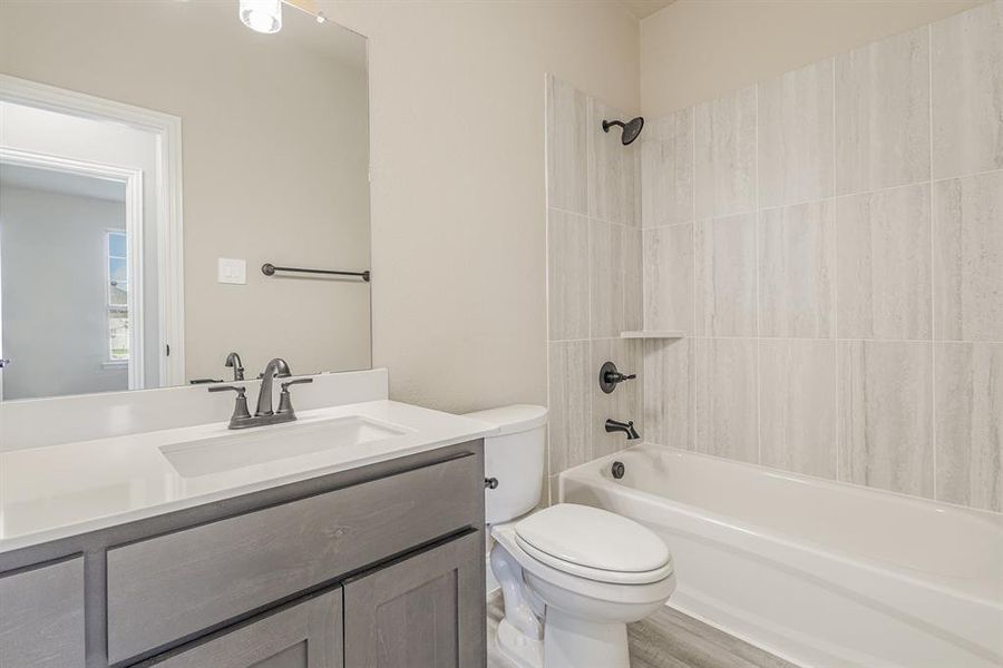 Full bathroom with vanity, toilet, tiled shower / bath combo, and wood-type flooring