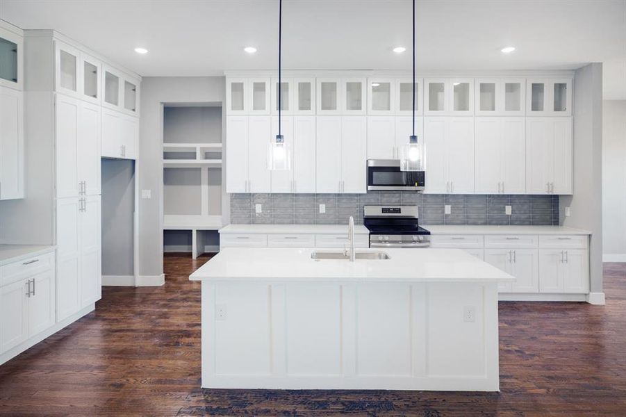 Kitchen with backsplash, stainless steel appliances, glass insert cabinets, white cabinets, and recessed lighting Kitchen with backsplash, stainless steel appliances, glass insert cabinets, white cabinets, and recessed lighting