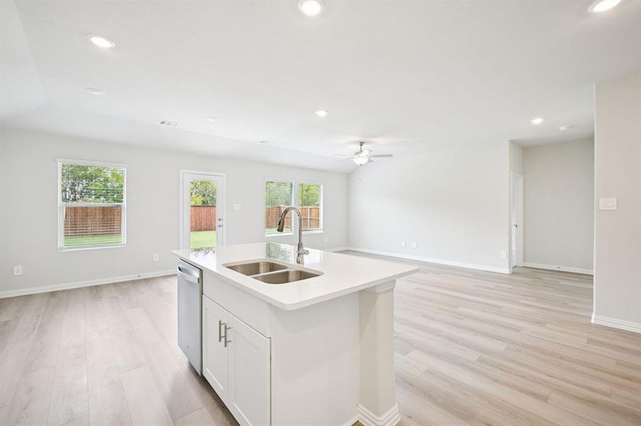 Kitchen featuring white cabinetry, open floor plan, light wood-style flooring, recessed lighting, and light stone counters