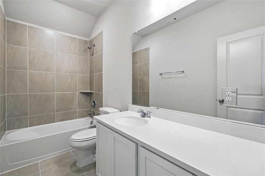 Bathroom featuring  shower combination, vanity, light tile patterned flooring, and lofted ceiling